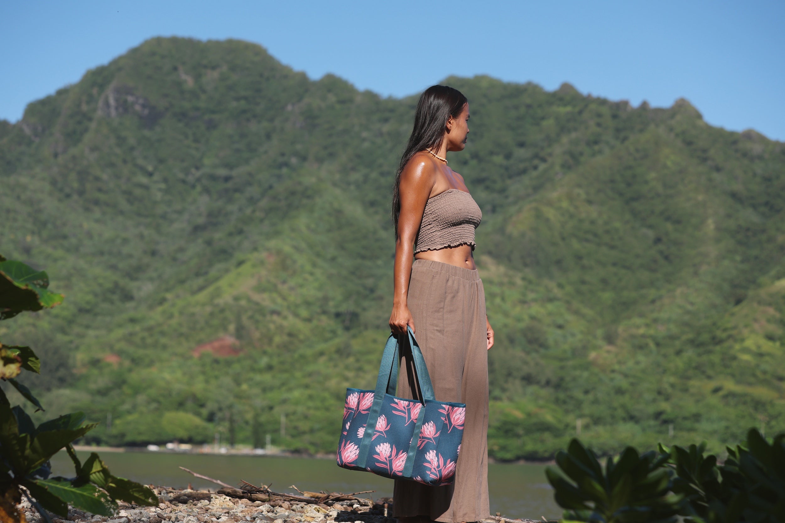 woman carrying a rich teal neoprene tote with blush colored protea print