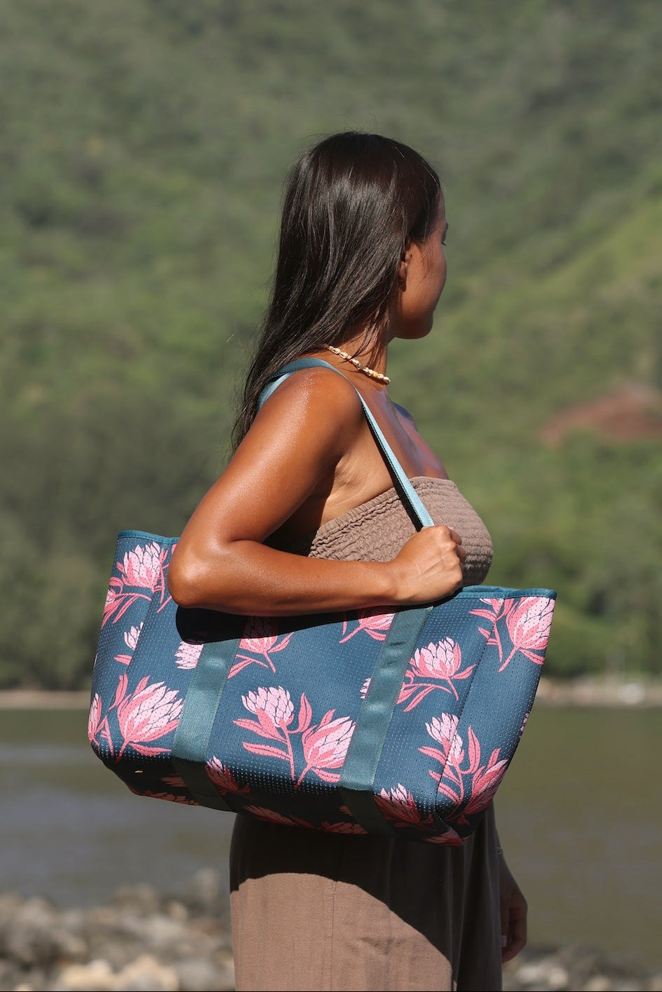 woman carrying a rich teal neoprene tote with blush colored protea print