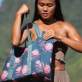 woman carrying a rich teal neoprene tote with blush colored protea print