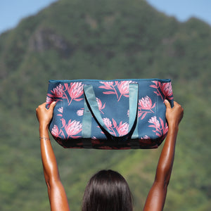 woman carrying a rich teal neoprene tote with blush colored protea print
