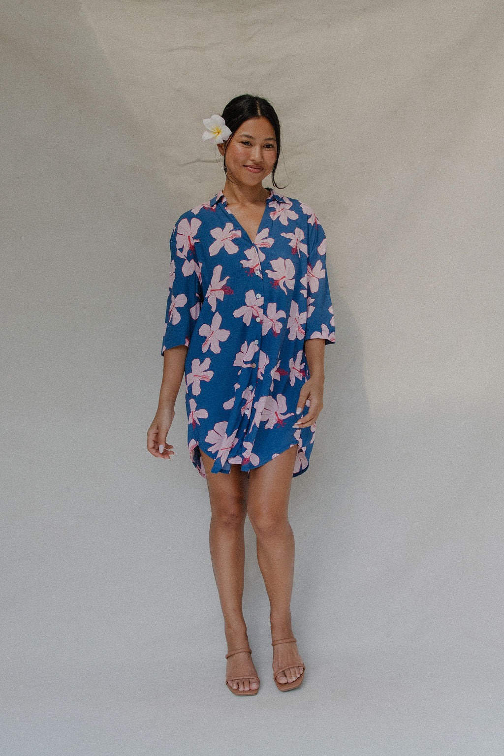 Woman with brown hair wearing mid sleeve button up dress in navy and hibiscus print