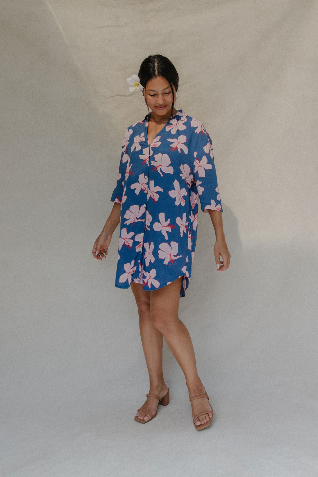 Woman with brown hair wearing mid sleeve button up dress in navy and hibiscus print