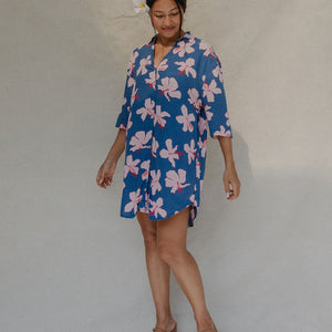 Woman with brown hair wearing mid sleeve button up dress in navy and hibiscus print