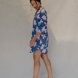 Woman with brown hair wearing mid sleeve button up dress in navy and hibiscus print