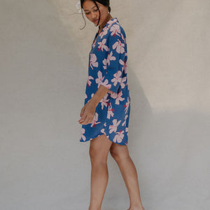 Woman with brown hair wearing mid sleeve button up dress in navy and hibiscus print