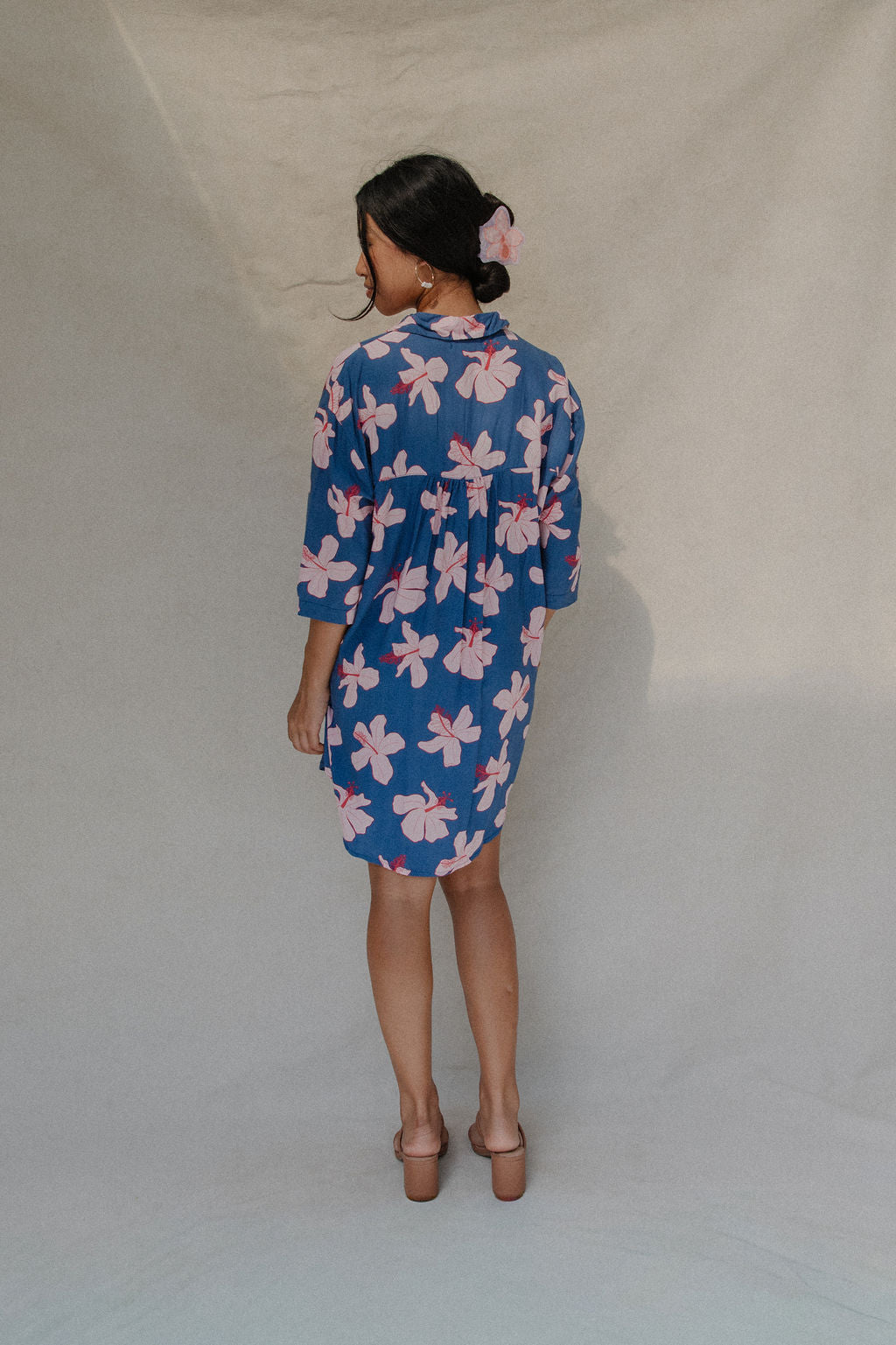 Woman with brown hair wearing mid sleeve button up dress in navy and hibiscus print
