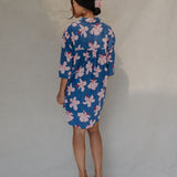 Woman with brown hair wearing mid sleeve button up dress in navy and hibiscus print