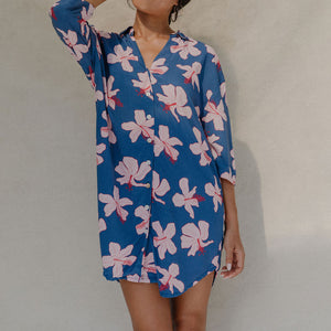 Woman with brown hair wearing mid sleeve button up dress in navy and hibiscus print