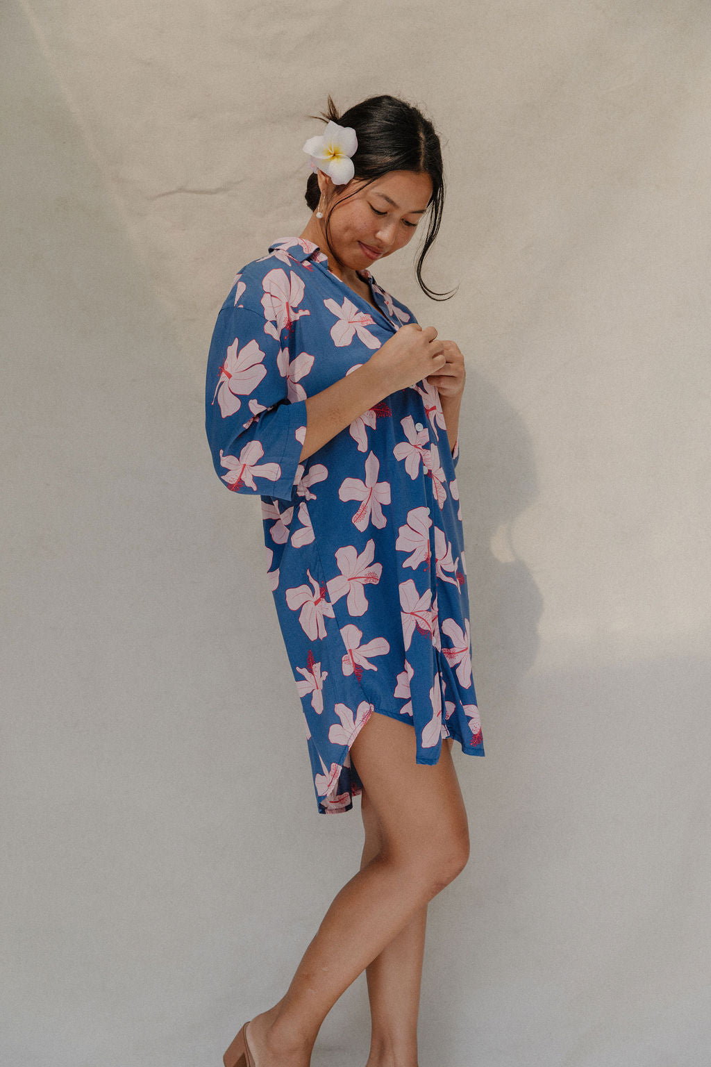 Woman with brown hair wearing mid sleeve button up dress in navy and hibiscus print