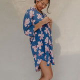 Woman with brown hair wearing mid sleeve button up dress in navy and hibiscus print
