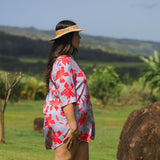 woman with brown hair wearing a mid length button up dress with periwinkle background and bright red hibiscus print.