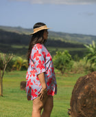 woman with brown hair wearing a mid length button up dress with periwinkle background and bright red hibiscus print.