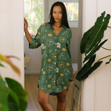 woman with brown hair wearing lush green button up dress with mid length sleeves and puakenikeni print