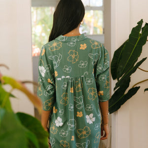 woman with brown hair wearing lush green button up dress with mid length sleeves and puakenikeni print