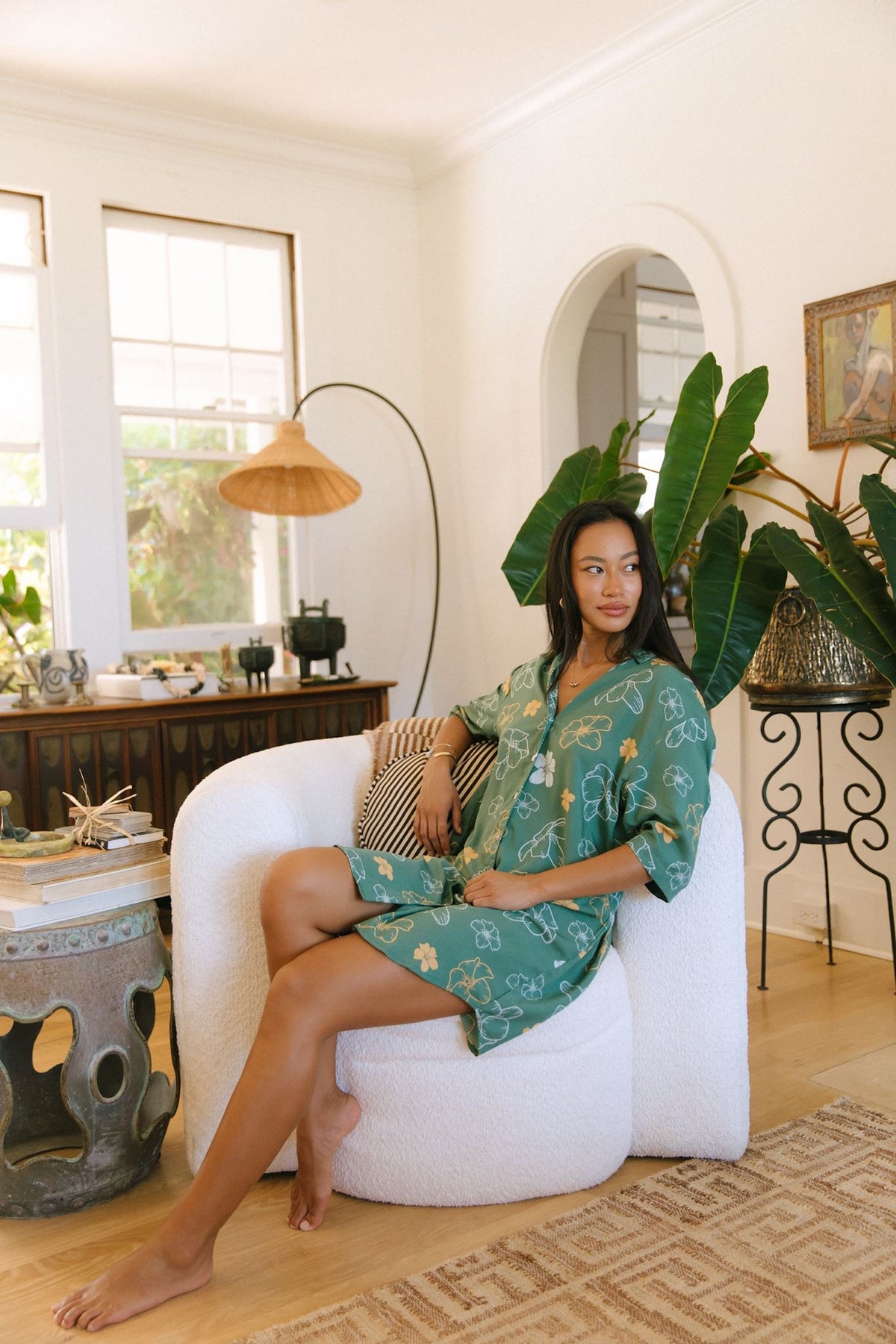 woman with brown hair wearing lush green button up dress with mid length sleeves and puakenikeni print