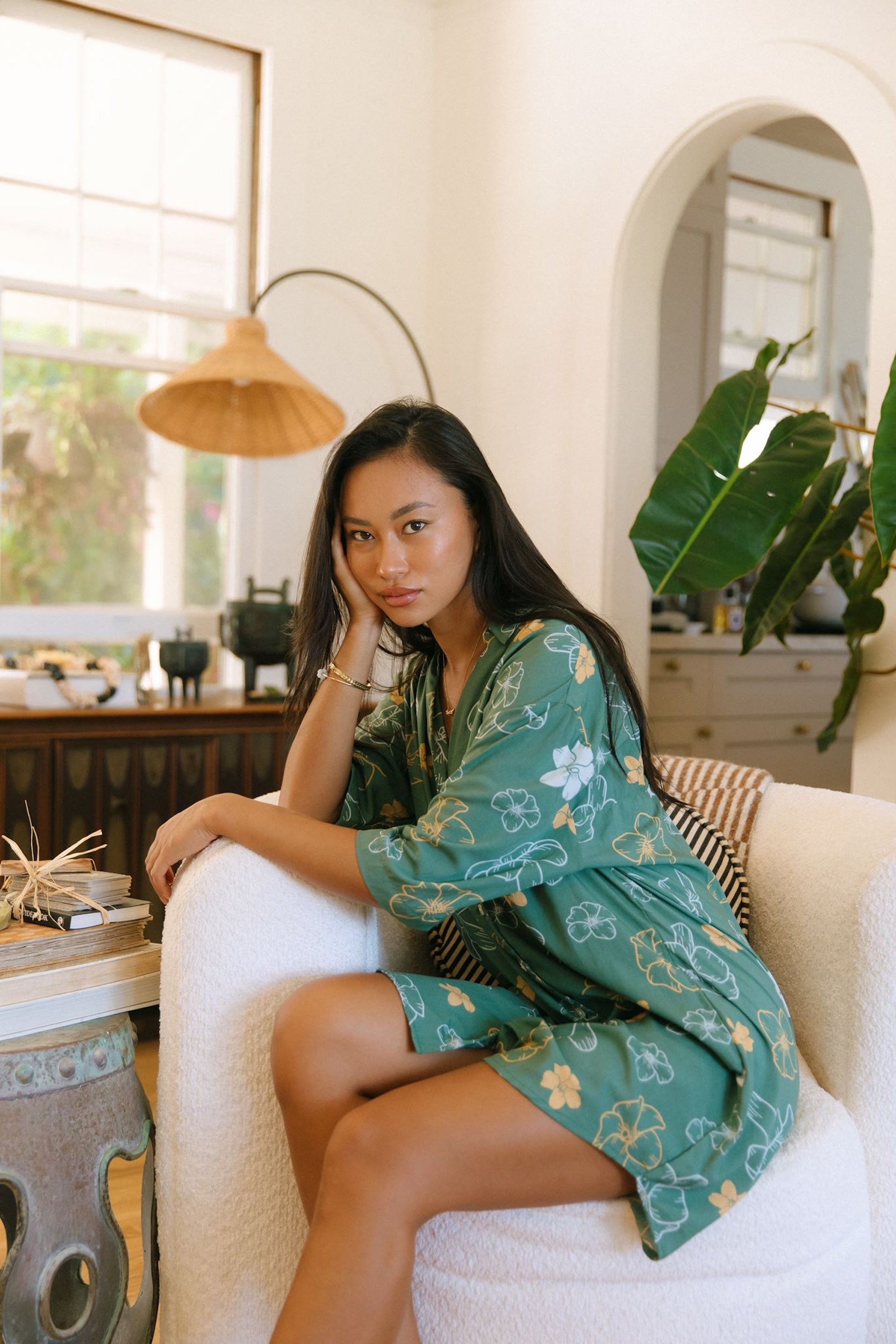 woman with brown hair wearing lush green button up dress with mid length sleeves and puakenikeni print