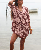 Woman with brown hair wearing a button up dress in blush and brown hibiscus print