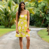 woman wearing a bright green tie back mini dress with orchid print