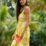 woman wearing a bright green tie back mini dress with orchid print
