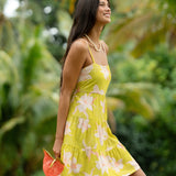 woman wearing a bright green tie back mini dress with orchid print