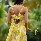 woman wearing a bright green tie back mini dress with orchid print