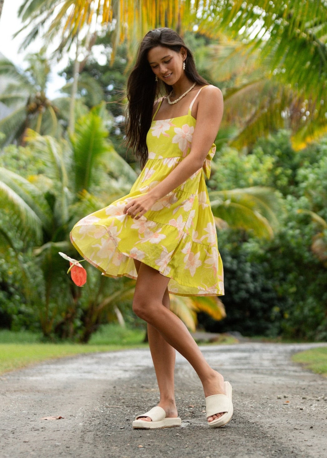 woman wearing a bright green tie back mini dress with orchid print