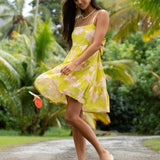 woman wearing a bright green tie back mini dress with orchid print