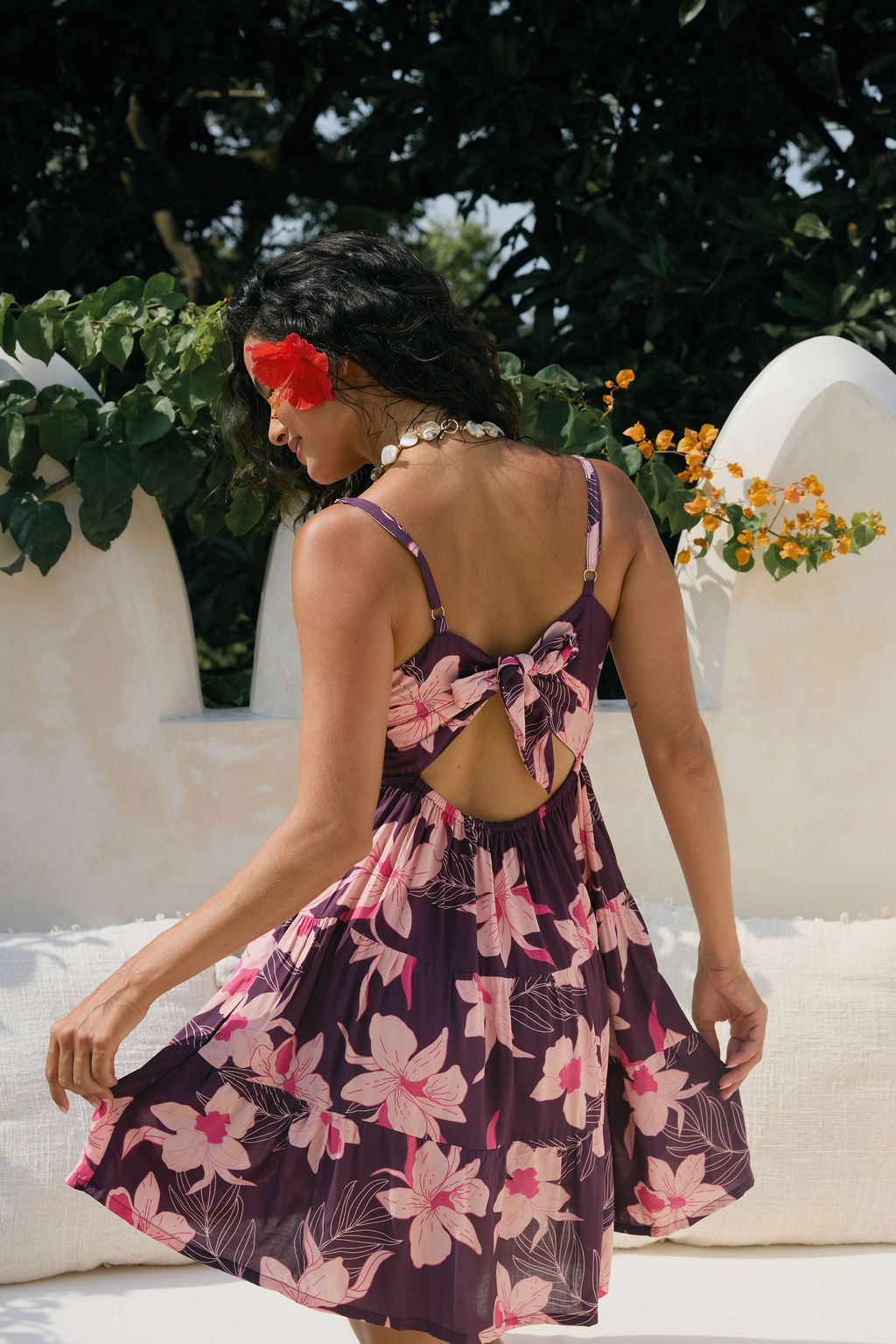 woman wearing dark purple mini dress with tie back detail with orchid print