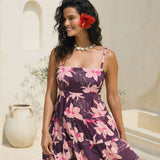 woman wearing dark purple mini dress with tie back detail with orchid print