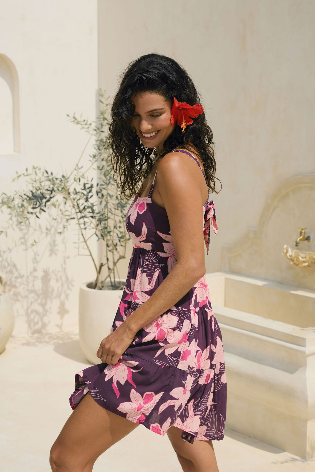 woman wearing dark purple mini dress with tie back detail with orchid print