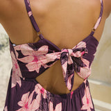 woman wearing dark purple mini dress with tie back detail with orchid print