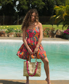 woman with brown hair wearing a colorful mini dress with tropical lei print