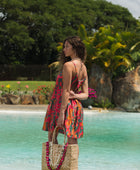 woman with brown hair wearing a colorful mini dress with tropical lei print