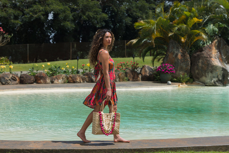 woman with brown hair wearing a colorful mini dress with tropical lei print