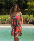 woman with brown hair wearing a colorful mini dress with tropical lei print