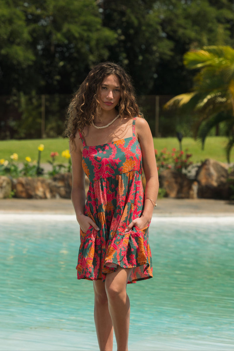 woman with brown hair wearing a colorful mini dress with tropical lei print