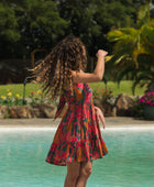 woman with brown hair wearing a colorful mini dress with tropical lei print