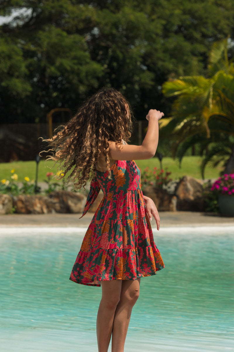 woman with brown hair wearing a colorful mini dress with tropical lei print
