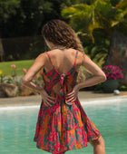 woman with brown hair wearing a colorful mini dress with tropical lei print