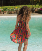 woman with brown hair wearing a colorful mini dress with tropical lei print