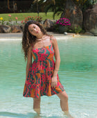 woman with brown hair wearing a colorful mini dress with tropical lei print