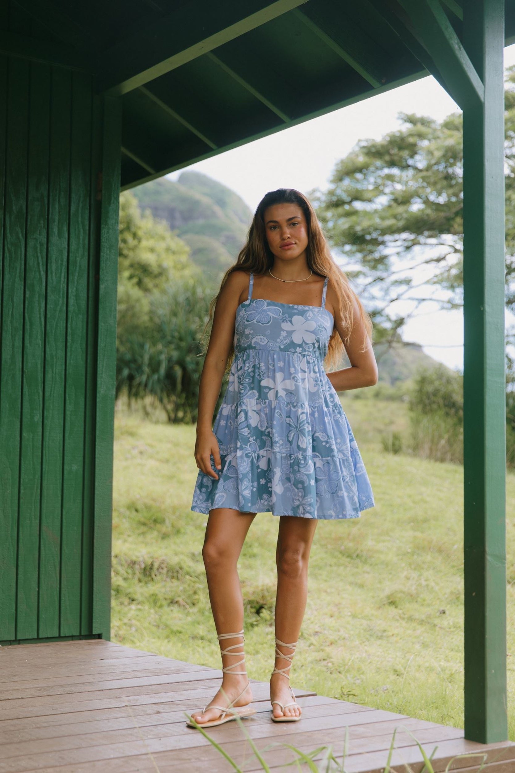 woman with brown hair wearing blue paniolo print mini dress with tie back detail