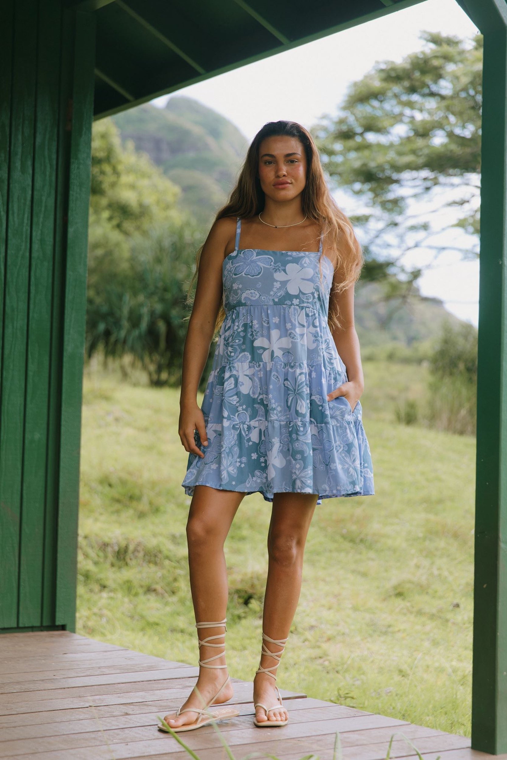 woman with brown hair wearing blue paniolo print mini dress with tie back detail