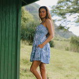 woman with brown hair wearing blue paniolo print mini dress with tie back detail