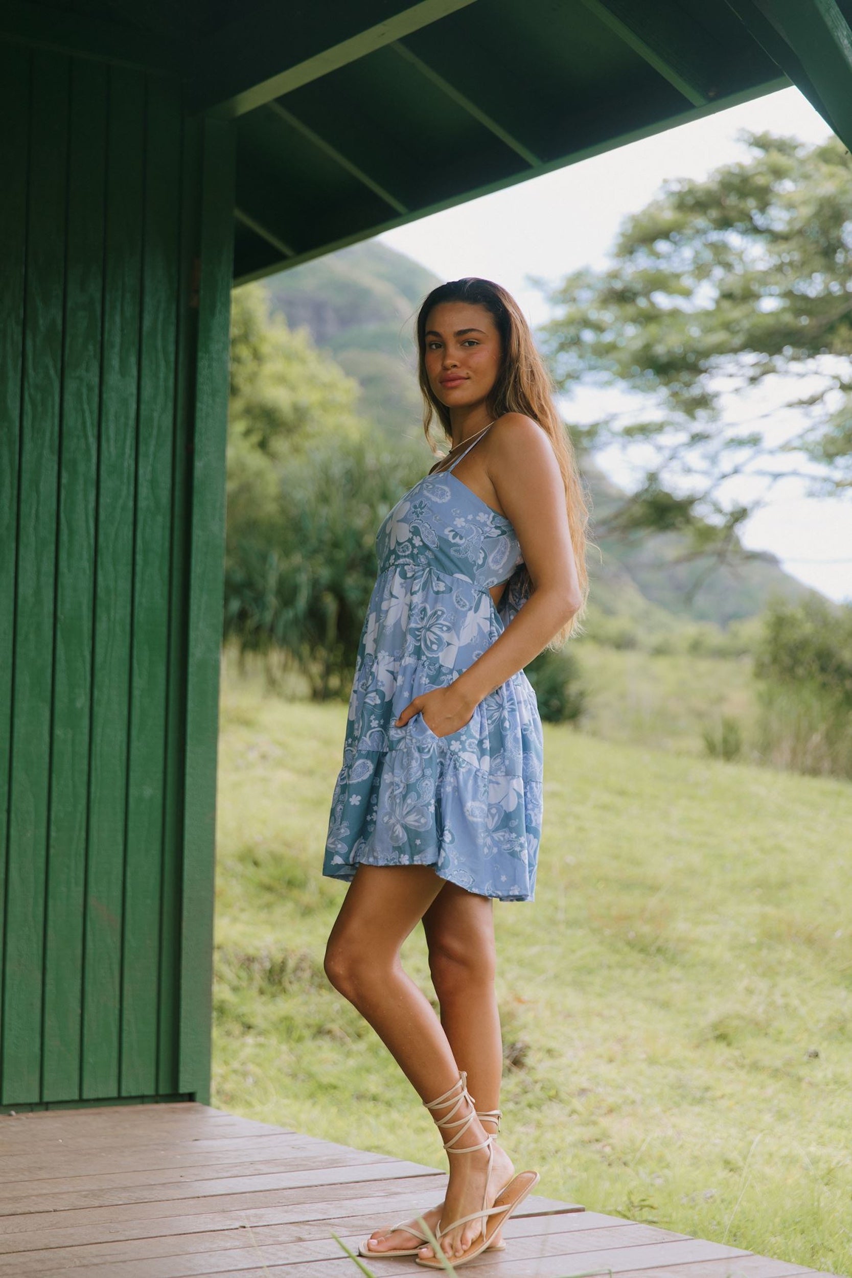 woman with brown hair wearing blue paniolo print mini dress with tie back detail