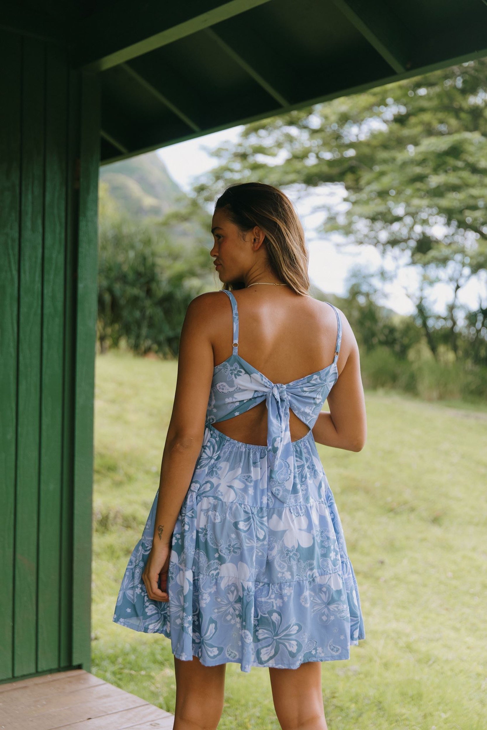 woman with brown hair wearing blue paniolo print mini dress with tie back detail