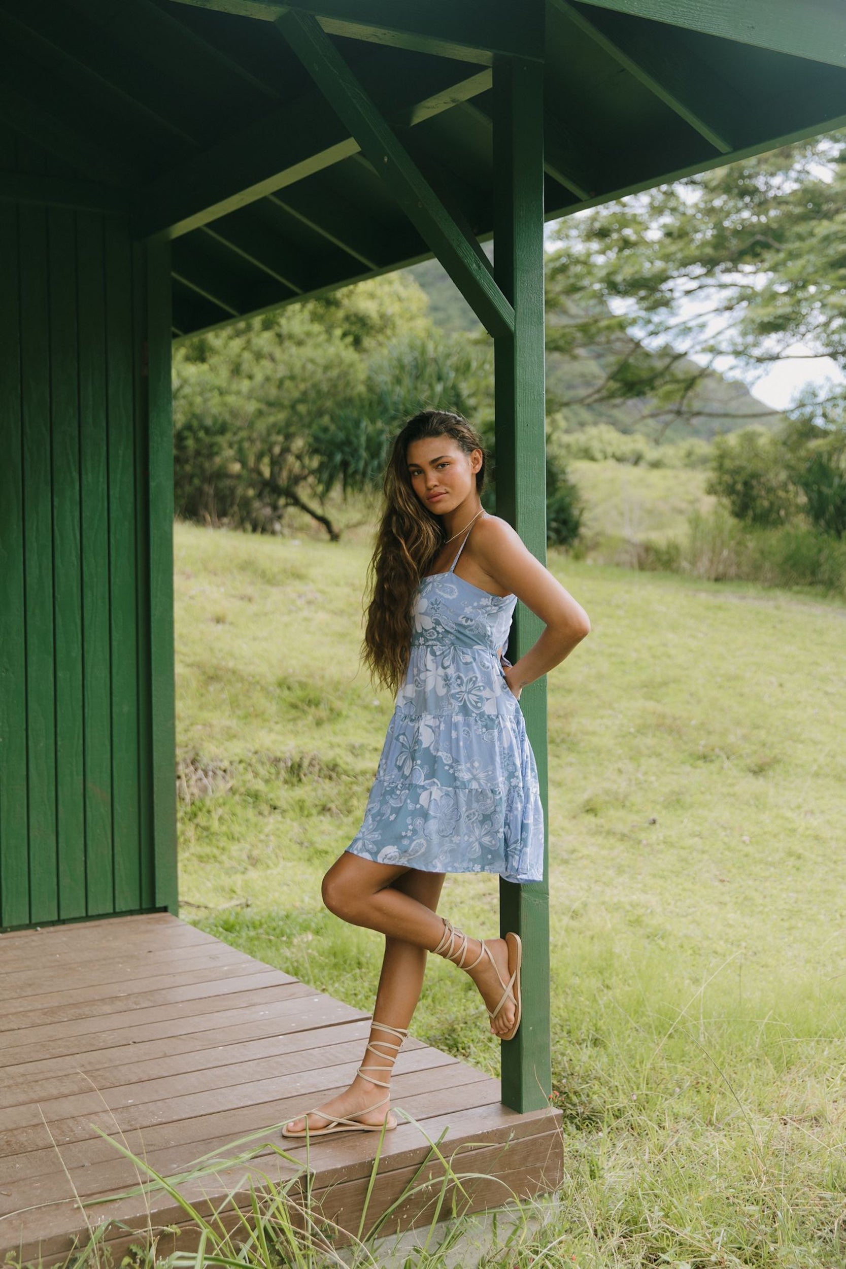 woman with brown hair wearing blue paniolo print mini dress with tie back detail
