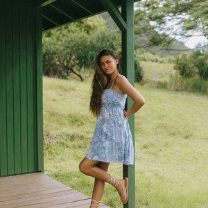 woman with brown hair wearing blue paniolo print mini dress with tie back detail