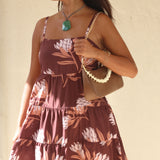 woman wearing a brown colored mini dress with tie back detail and protea print
