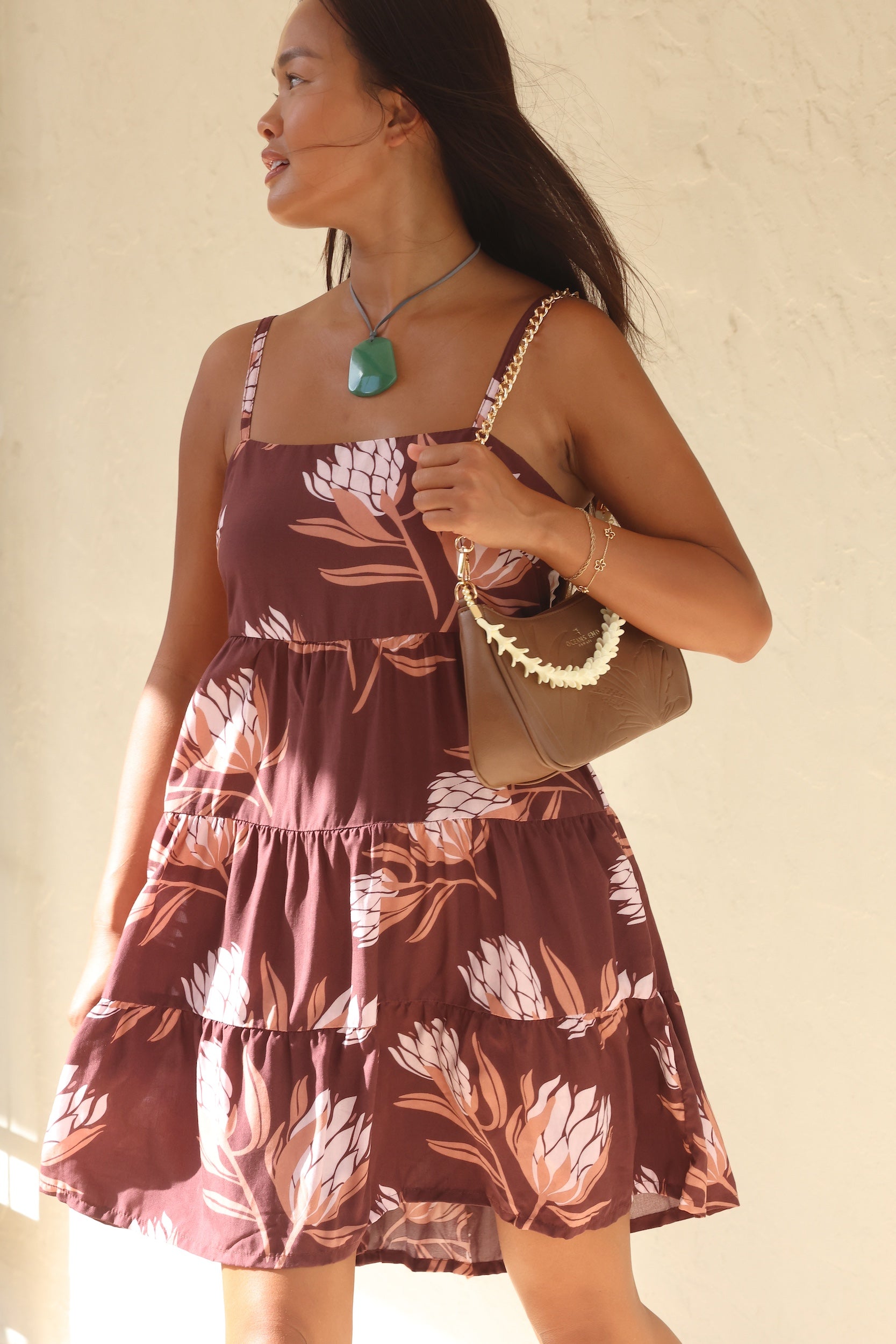 woman wearing a brown colored mini dress with tie back detail and protea print
